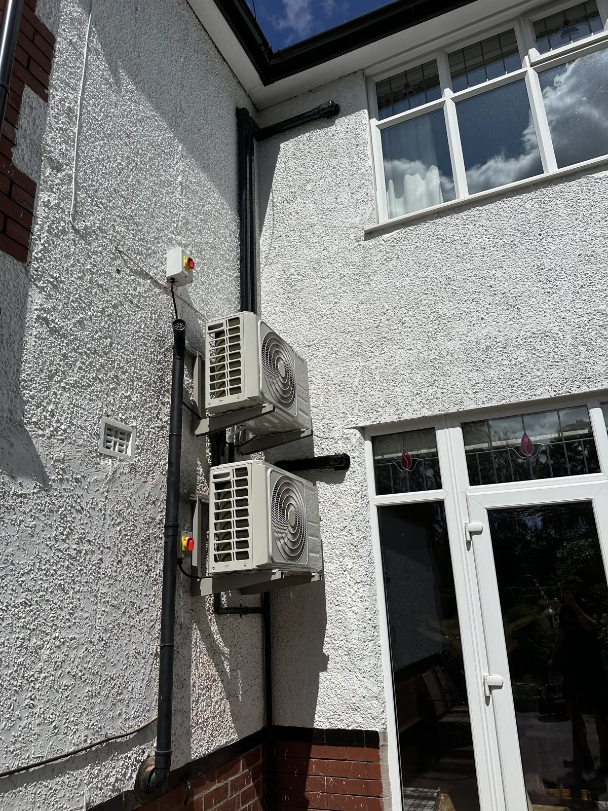 Two air conditioning units mounted on a house wall